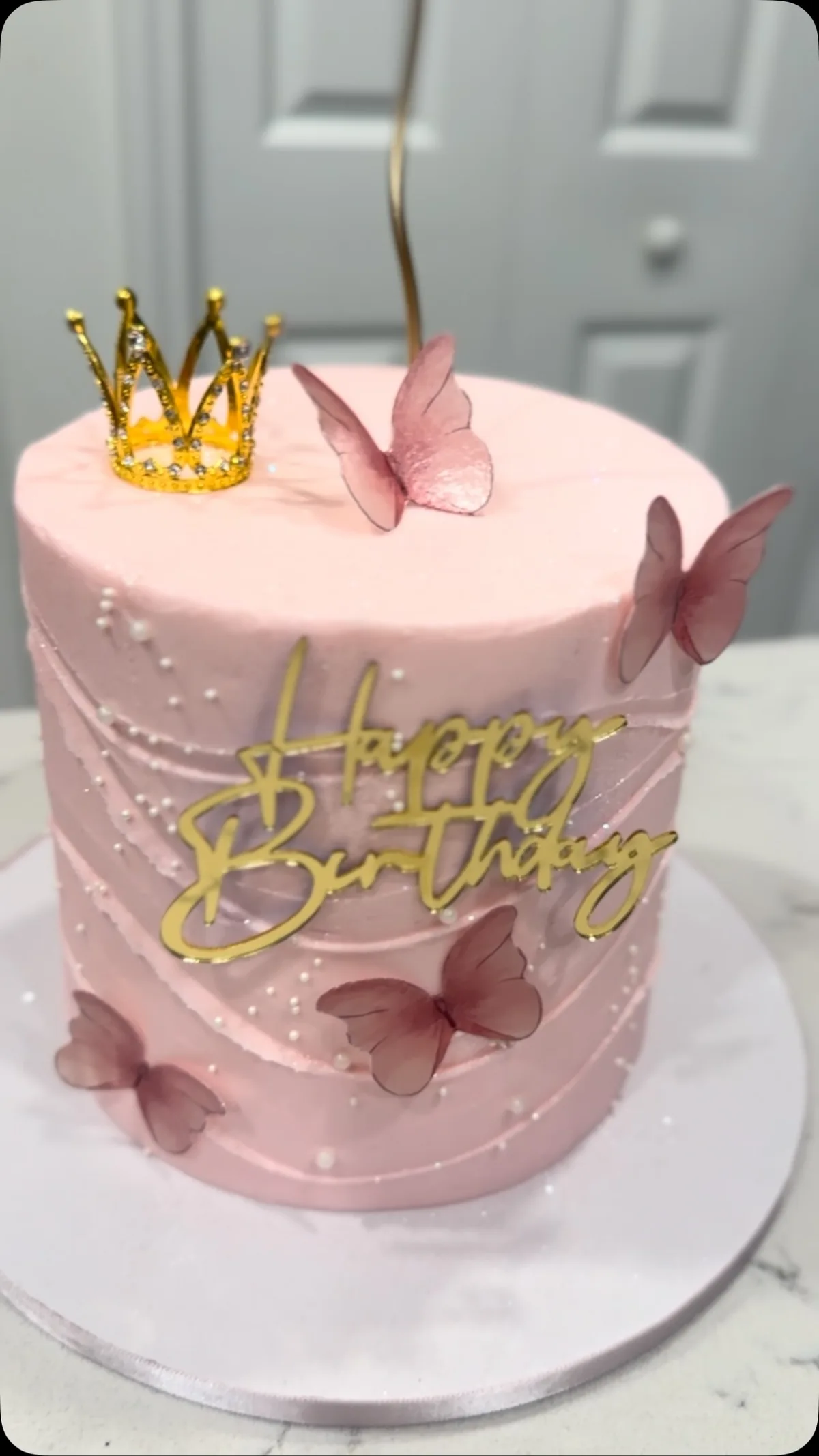 Pink birthday cake with gold crown and butterflies